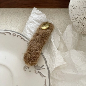 Close-up of brown plush hair clip with an oval gold metal plaque and engraved text