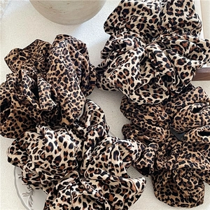 Close-up of four oversized leopard print scrunchies with pleated chiffon texture