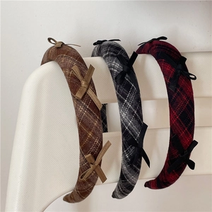 Close-up of thick plaid headbands with bows in brown, black, and red checkered fabric