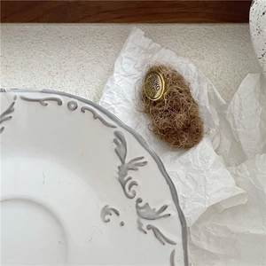 Macro shot of vintage plush brown fabric hair clip with oval gold metal logo branding