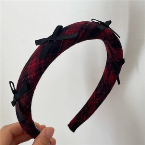 Detail of red and black plaid padded headband with small black fabric bow embellishments