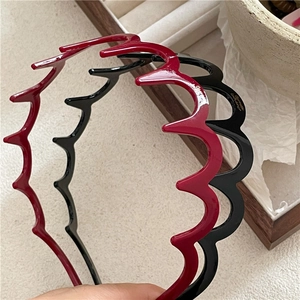 Close-up of wavy plastic hairbands in red and black with high gloss finish and tooth grip