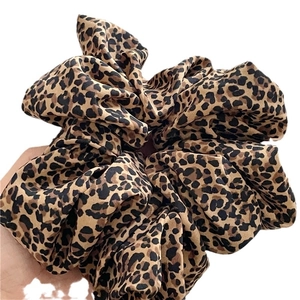 Oversized leopard print scrunchie for women made of textured fabric in a stylish hand-held view