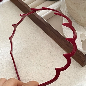 Close-up of wine red wavy headband with a glossy finish and serrated teeth design
