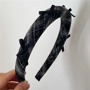 Close-up of thick checkered sponge headband with black silk bows in a vintage style