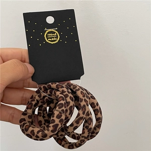 Close-up of leopard print elastic hair ties set with Hand Made brand packaging card
