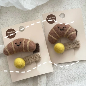 Close-up of wool felt croissant hair clips with cute embroidered smiles on card
