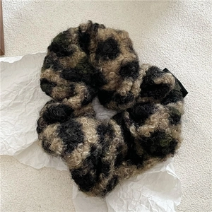 Gros plan d'un chouchou en fausse fourrure bouclée avec motif camouflage marron et vert