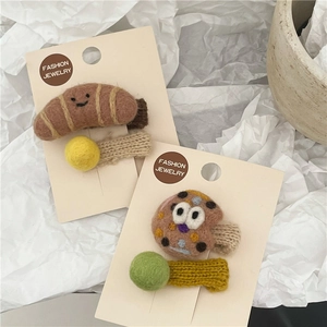 Close-up of wool felt croissant and cookie hair clips on a display card with knit lining