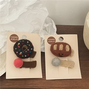 Detailed close-up of handmade felt bread smile face and doughnut hair clips on cards