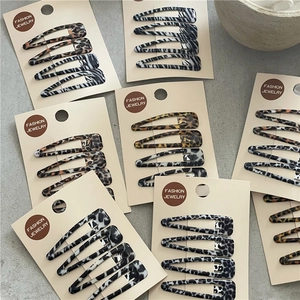 Détail de barrettes à imprimé animal léopard et vache sur leur support de vente