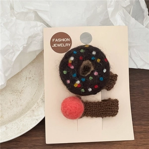 Detail of wool felt donut and red ball hair clip set on a fashion jewelry display card