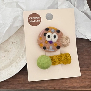 Detailed view of handmade felt bread and pom-pom hair clips on display card