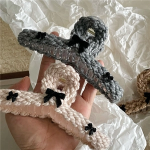 Detail of knit weave texture on hair claw clip with black bow accents in gray and beige