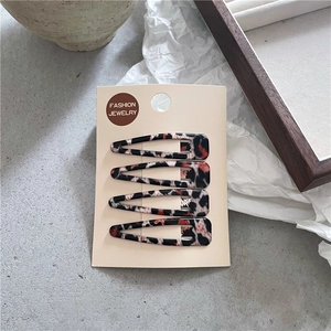 Détail de quatre barrettes à motif léopard sur carte avec des textures d'acétate