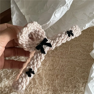 Detail of knit hair claw clip featuring black velvet bows and soft beige wool texture