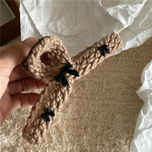 Detail of light brown knitted hair claw clip featuring three elegant black velvet bows