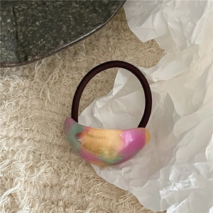 Detailansicht eines marmorierten Acetat-Haargummis mit bunten Tie-Dye-Mustern und Gummiband