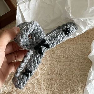 Detail of grey knitted hair claw clip featuring black bows and acrylic inner teeth