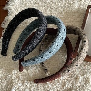 Detailed view of four handmade polka dot tweed headbands in various colors on a plush rug