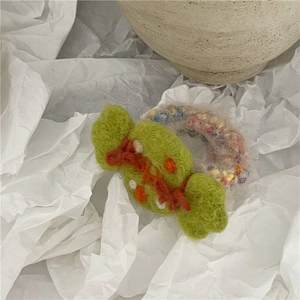 Detailed macro of a green felt candy-shaped hair tie with a colorful elastic towel ring