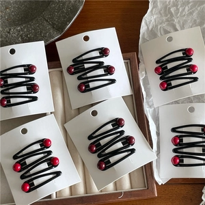 Set of three black snap hair clips with burgundy round beads on a display card