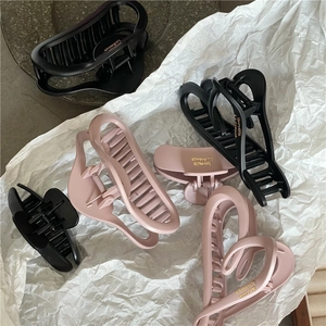 Detailed view of matte pink and black hair claws with hollow heart and oval designs