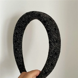 Close-up of thick tweed headband featuring a grey and white weave with black polka dots