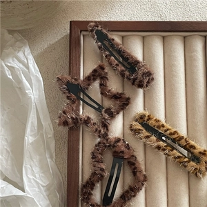 Macro detail of various plush leopard print hair clips in star and rectangle shapes