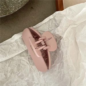 Detail of matte pink hollow heart hair claw clip with golden text on white paper