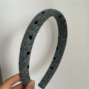 Close-up detail of grey woolen headband with decorative 3D black polka dots on fabric