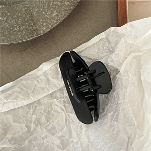 Close-up of matte black hair claw clip with golden LA France text on crinkled paper