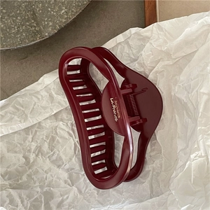 Close-up of elegant burgundy hollow heart hair claw clip with glossy finish and metal spring