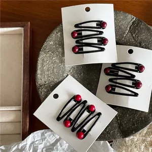 Set of minimalist black metal waterdrop hair clips with red beads on display card