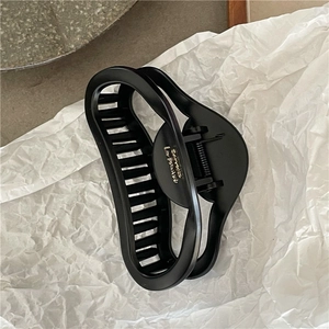Detail of matte black hollow heart hair claw with gold logo and durable metal spring