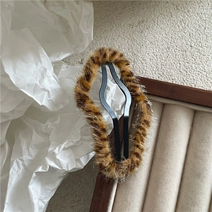 Detail of plush leopard print hair clip showing soft faux fur texture on a wooden box
