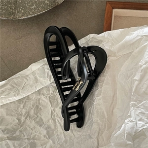 Detailed view of matte black heart-shaped hair claw clip with golden lettering accents