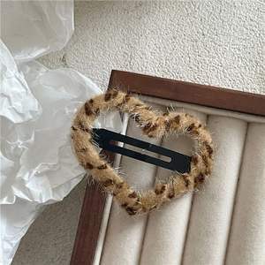 Close-up of heart-shaped plush leopard print hair clip on a wooden jewelry tray