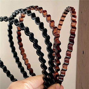 Close-up of wavy plastic hairbands in black and amber brown with a glossy finish