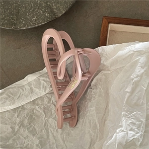 Close-up of matte light pink hair claw clip with gold lettering on elegant background