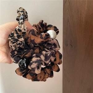 Détail d'un chouchou en tissu léopard avec des perles décoratives noires et blanches