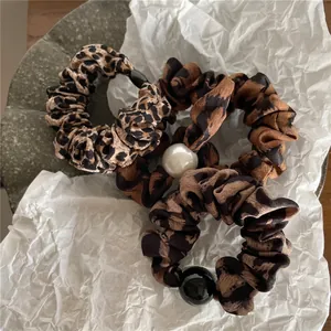 Trois chouchous en tissu imprimé léopard avec détails de perles sur plateau en pierre