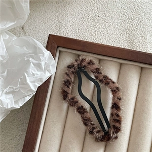 Detail of plush leopard print hair clip with soft faux fur texture on a wooden tray