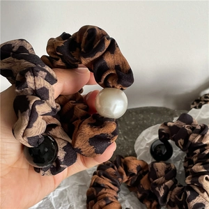 Vue détaillée du chouchou en tissu imprimé léopard avec perles décoratives et noires