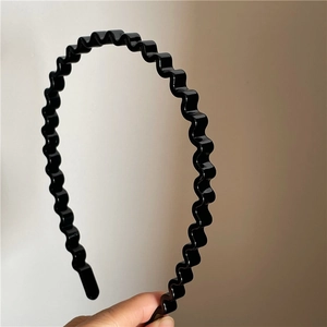 Close-up of black wavy hair hoop made of glossy plastic for daily minimalist hair styling