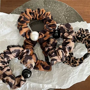 Détail de chouchous à imprimé léopard avec perles décoratives sur une surface texturée