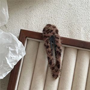 Macro shot of brown leopard print plush hair clip on a velvet jewelry tray