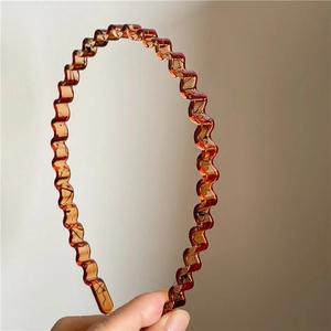 Close-up of amber wavy resin headband with elegant black textured patterns