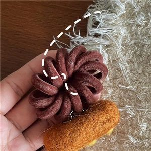 Detailed macro of wool felt hair band accessory with warm textured brown spiral ring