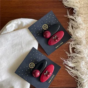 Sweet red cherry hair clips set with oval and round bead designs on wooden background